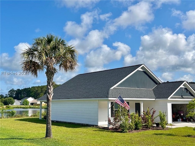 view of front of home with a garage, a water view, and a front lawn