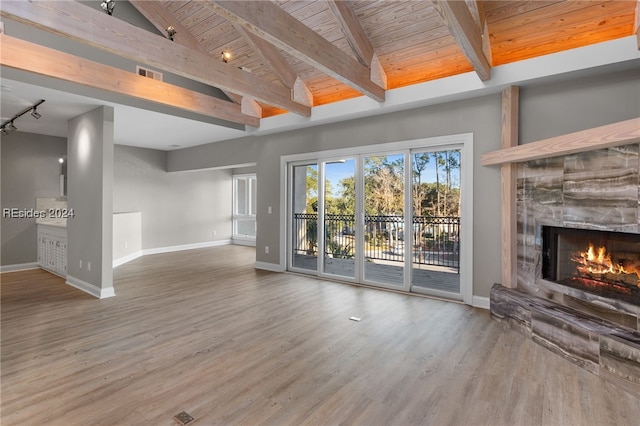 unfurnished living room with a stone fireplace, wood ceiling, high vaulted ceiling, beam ceiling, and hardwood / wood-style floors