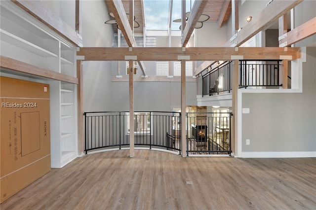 interior space featuring a high ceiling, hardwood / wood-style flooring, a fireplace, and beam ceiling