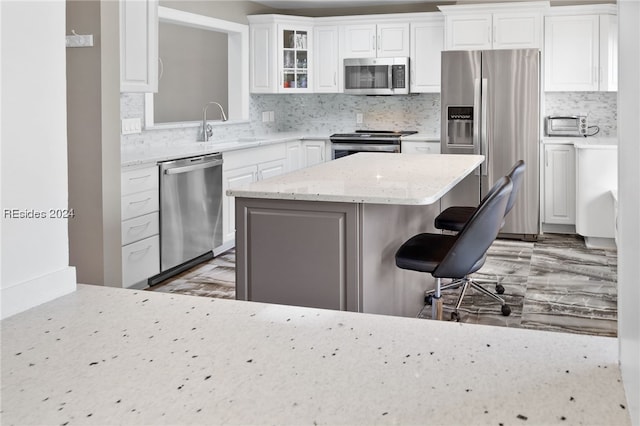 kitchen with stainless steel appliances, sink, white cabinets, and a breakfast bar