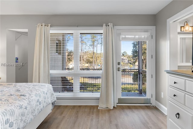 bedroom featuring multiple windows, access to outside, and light hardwood / wood-style floors