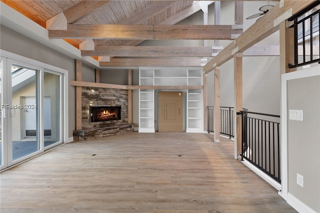 unfurnished living room with vaulted ceiling with beams, wood ceiling, a stone fireplace, and hardwood / wood-style flooring