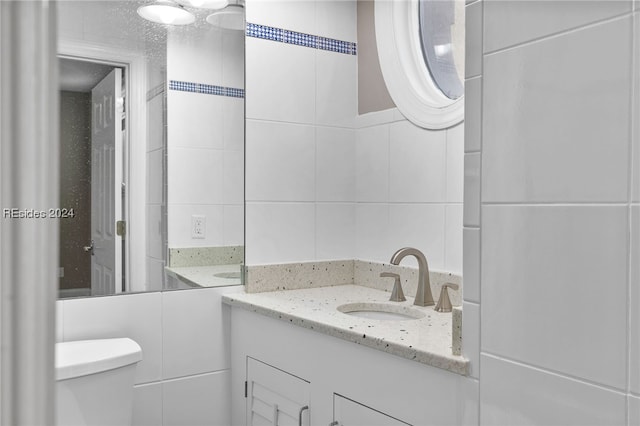 bathroom with tile walls, vanity, and toilet