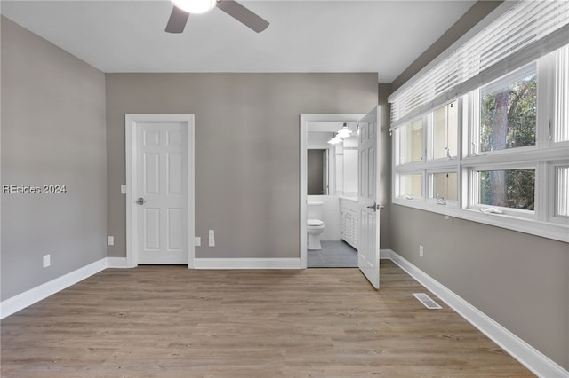 unfurnished bedroom with ceiling fan, ensuite bathroom, and light wood-type flooring