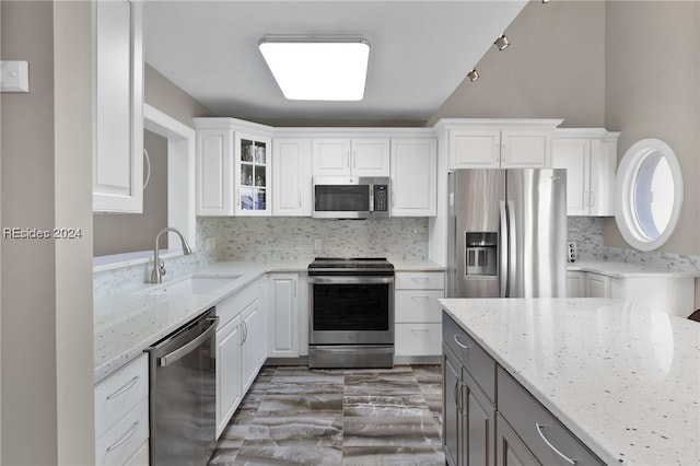 kitchen featuring light stone counters, stainless steel appliances, sink, and white cabinets