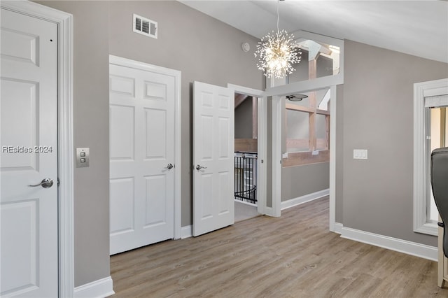 interior space with an inviting chandelier, light hardwood / wood-style floors, and lofted ceiling