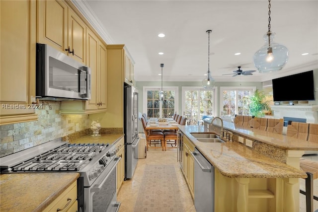 kitchen featuring appliances with stainless steel finishes, sink, a kitchen breakfast bar, hanging light fixtures, and a center island with sink