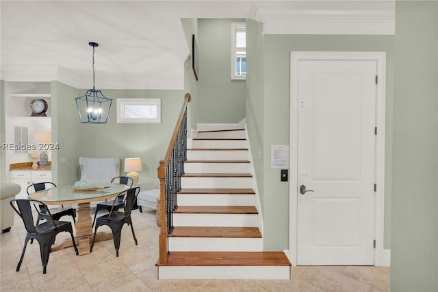 stairs with ornamental molding, built in features, and an inviting chandelier