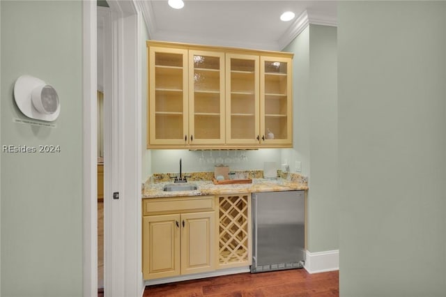 bar with sink, stainless steel refrigerator, light stone counters, ornamental molding, and dark hardwood / wood-style flooring