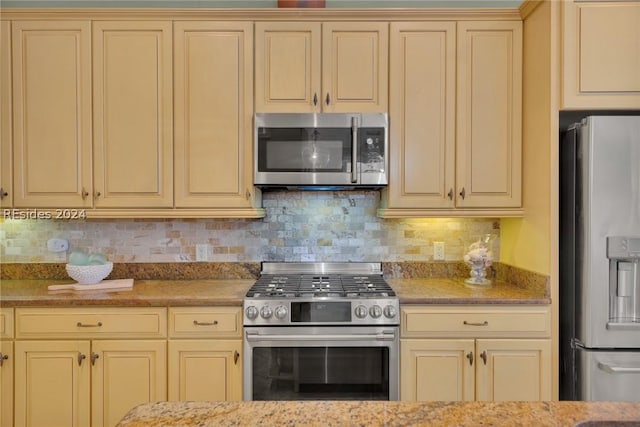 kitchen featuring light stone counters, backsplash, and appliances with stainless steel finishes