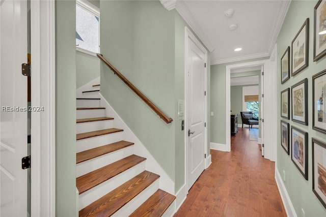 staircase featuring hardwood / wood-style flooring, crown molding, and a wealth of natural light