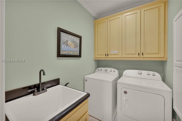 clothes washing area featuring sink, ornamental molding, cabinets, and washing machine and clothes dryer