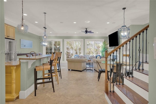 kitchen featuring a kitchen bar, light stone counters, high end refrigerator, hanging light fixtures, and light brown cabinets