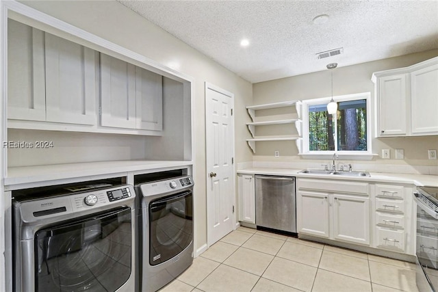 kitchen with sink, appliances with stainless steel finishes, independent washer and dryer, white cabinets, and light tile patterned flooring