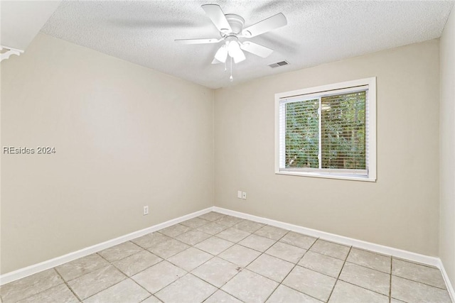 spare room with a textured ceiling, ceiling fan, and light tile patterned flooring