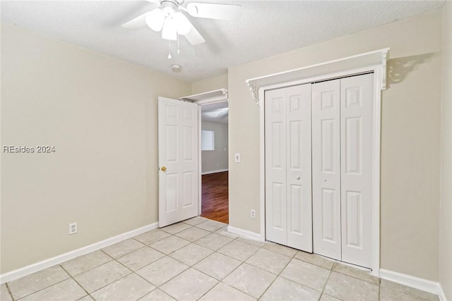 unfurnished bedroom with light tile patterned floors, a textured ceiling, ceiling fan, and a closet