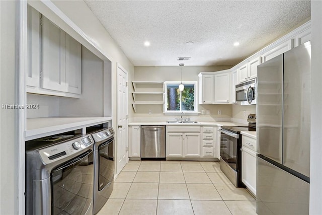 kitchen featuring sink, white cabinetry, hanging light fixtures, stainless steel appliances, and washing machine and dryer