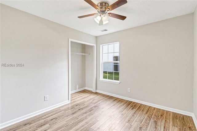 unfurnished bedroom featuring light wood-type flooring, ceiling fan, and a closet