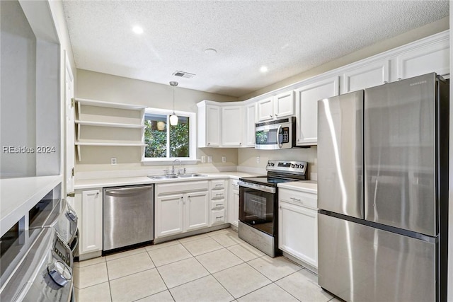 kitchen with sink, light tile patterned floors, stainless steel appliances, white cabinets, and decorative light fixtures