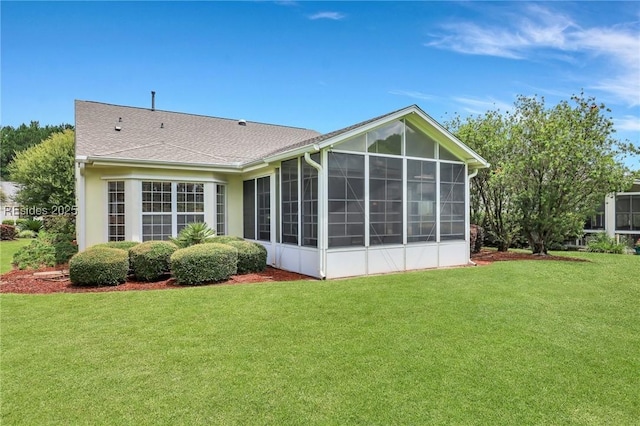 back of house featuring a sunroom and a lawn