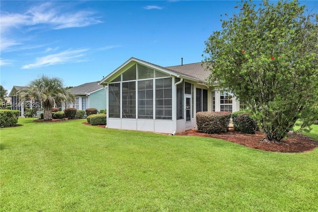 rear view of property featuring a yard and a sunroom