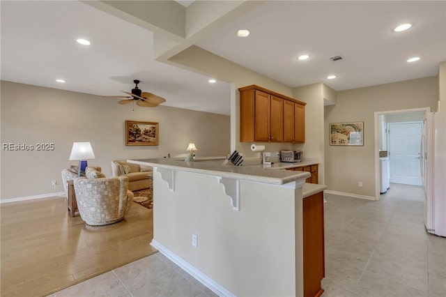 kitchen featuring ceiling fan, light tile patterned floors, a kitchen breakfast bar, and kitchen peninsula