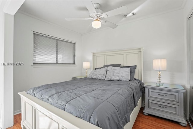 bedroom with ornamental molding, dark hardwood / wood-style floors, and ceiling fan