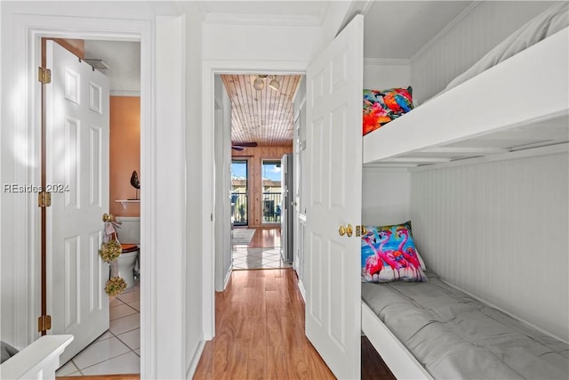 bedroom with ornamental molding, light hardwood / wood-style flooring, and wood walls