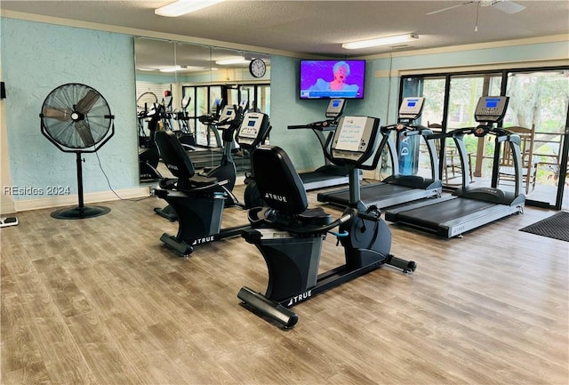 gym featuring ceiling fan, hardwood / wood-style floors, and a textured ceiling