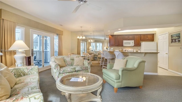 carpeted living room with ceiling fan with notable chandelier