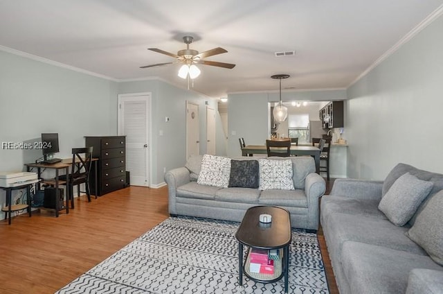 living room with hardwood / wood-style flooring, ornamental molding, and ceiling fan