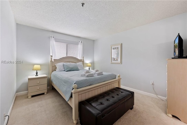 bedroom with light colored carpet and a textured ceiling