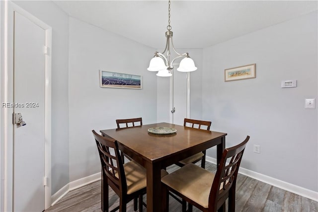 dining room with dark wood-type flooring and a chandelier