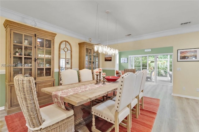 dining area with ornamental molding and light wood-type flooring