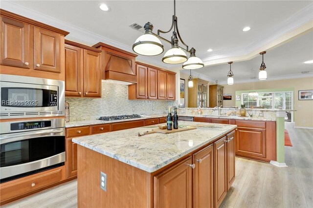 kitchen with a kitchen island, custom exhaust hood, appliances with stainless steel finishes, and pendant lighting