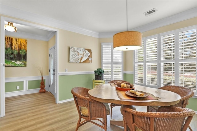 dining room with ornamental molding and light hardwood / wood-style floors