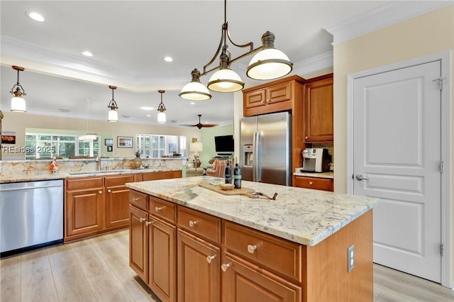 kitchen featuring appliances with stainless steel finishes, decorative light fixtures, sink, a center island, and crown molding