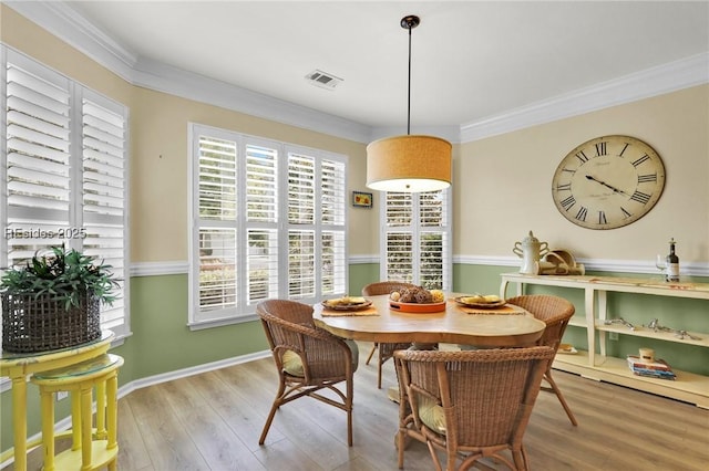 dining area featuring ornamental molding, plenty of natural light, and light hardwood / wood-style flooring