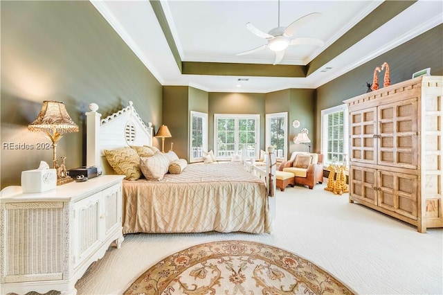 bedroom featuring a raised ceiling, crown molding, carpet floors, and ceiling fan