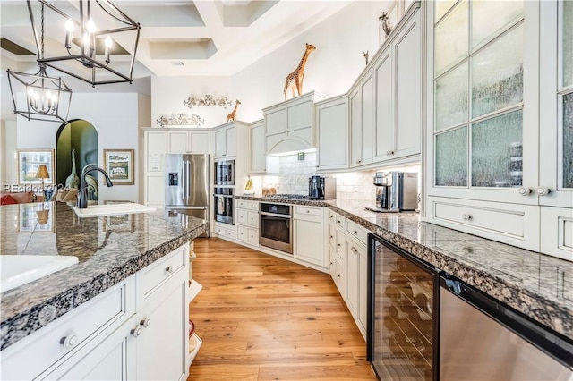 kitchen featuring sink, appliances with stainless steel finishes, wine cooler, tasteful backsplash, and coffered ceiling