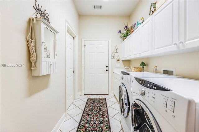 clothes washing area with light tile patterned flooring, cabinets, and washing machine and dryer