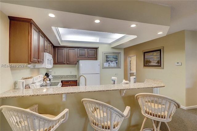 kitchen with white appliances, kitchen peninsula, and a kitchen bar