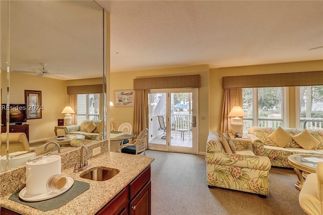 carpeted living room featuring ceiling fan, sink, and a wealth of natural light