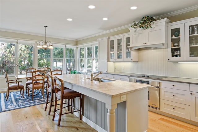 kitchen with sink, white cabinetry, a kitchen island with sink, black electric cooktop, and oven