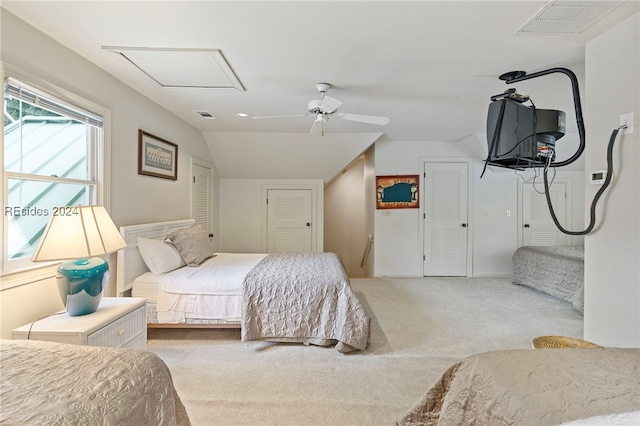 bedroom with multiple closets, vaulted ceiling, carpet, and ceiling fan