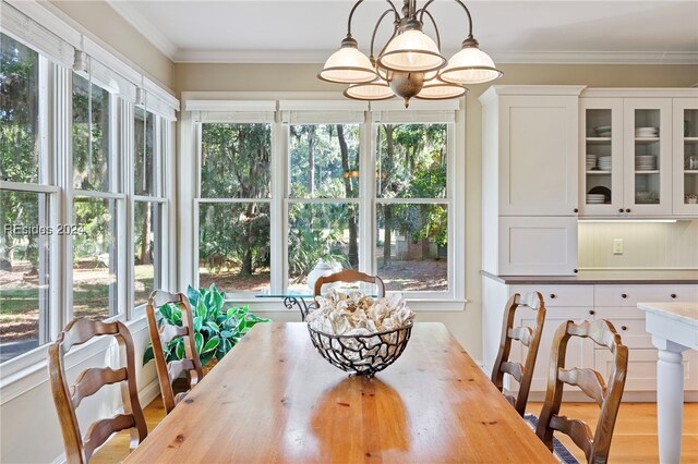 dining area with crown molding, a notable chandelier, and light wood-type flooring