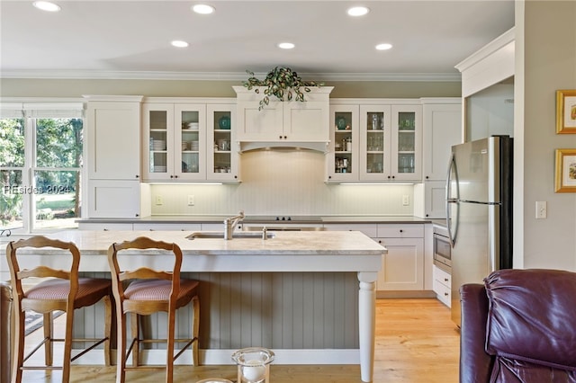 kitchen featuring sink, ornamental molding, appliances with stainless steel finishes, a kitchen breakfast bar, and white cabinets