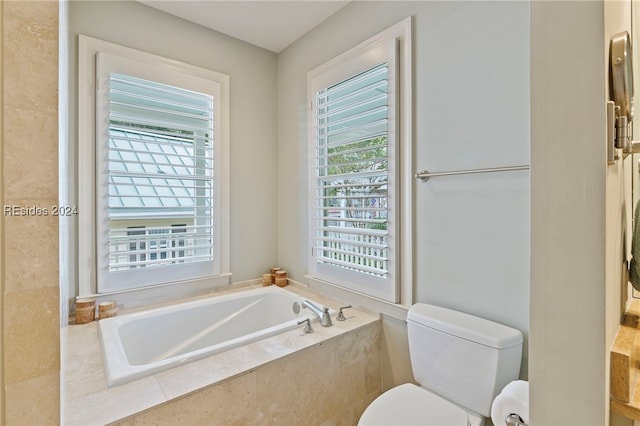 bathroom with tiled tub and toilet