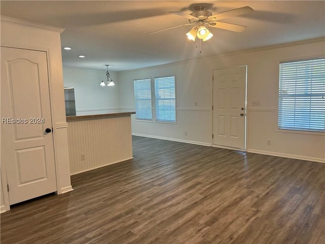 unfurnished room featuring ceiling fan with notable chandelier, dark wood-type flooring, and ornamental molding