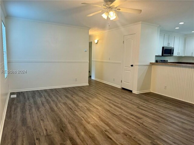 interior space with dark wood-type flooring, ornamental molding, and ceiling fan